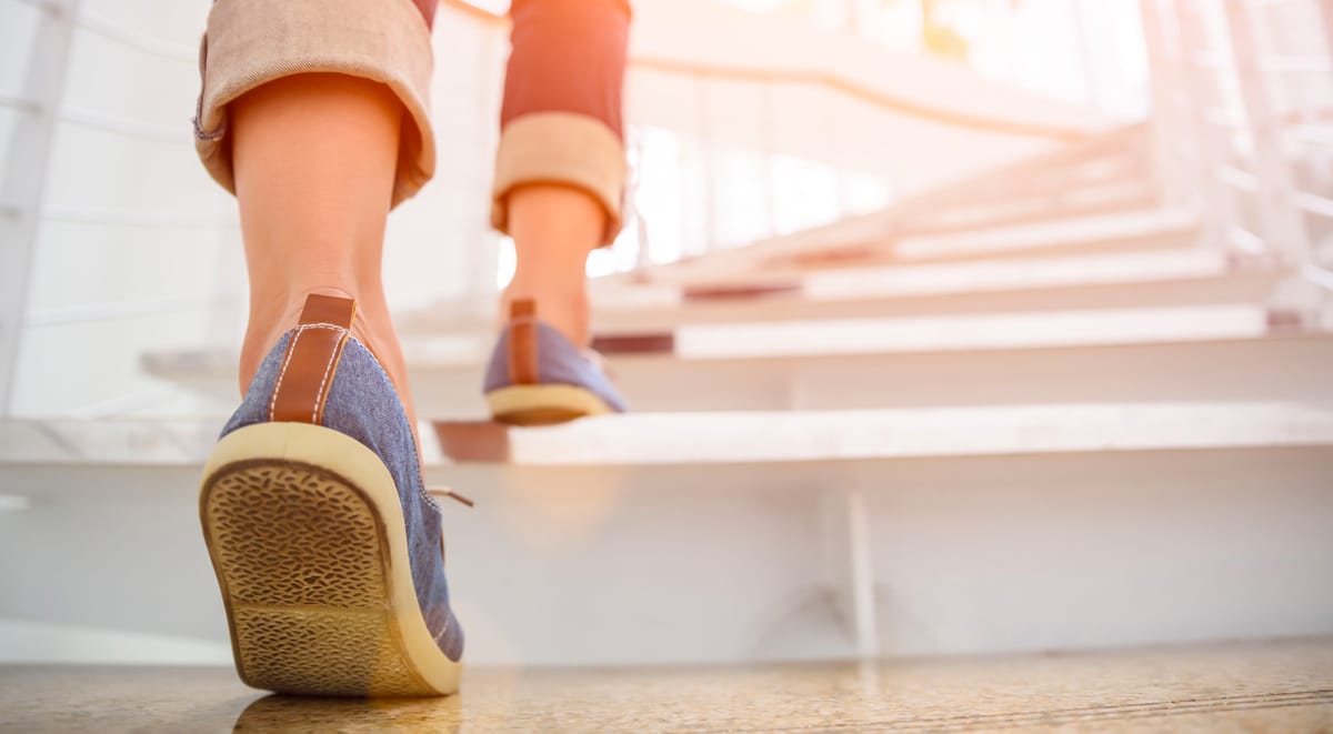 A closeup image of feet walking up a flight of stairs.