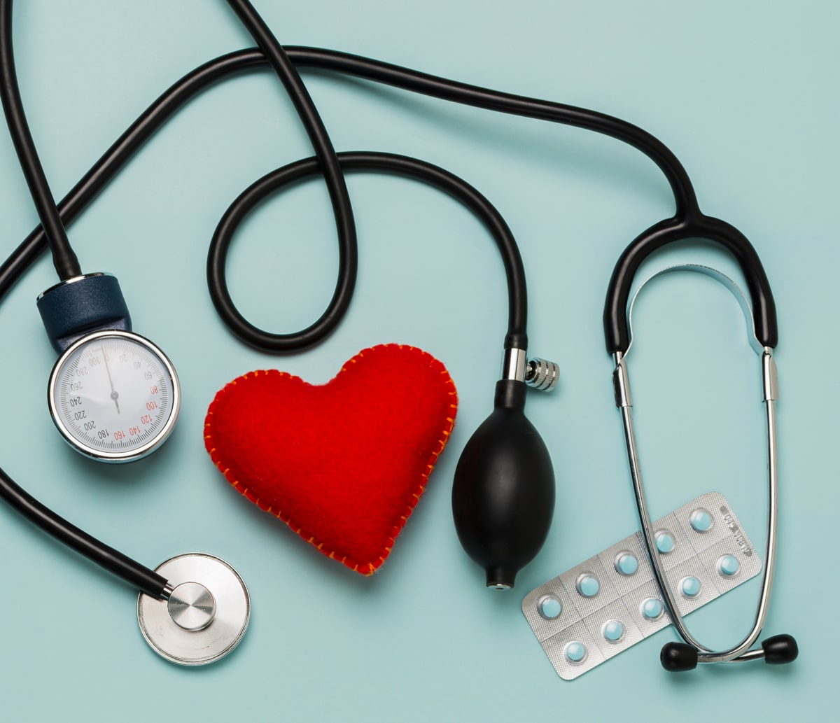 A red felt heart, surrounded by a stethoscope and pill packets.