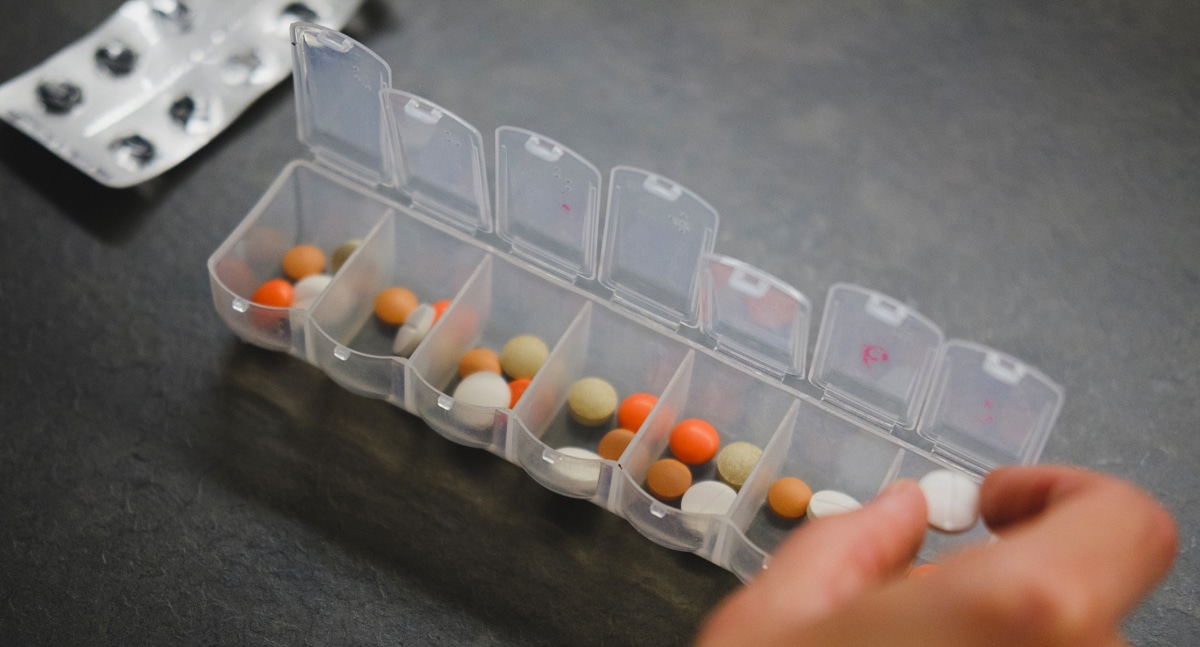 A close up image of pills being sorted into a pill container.