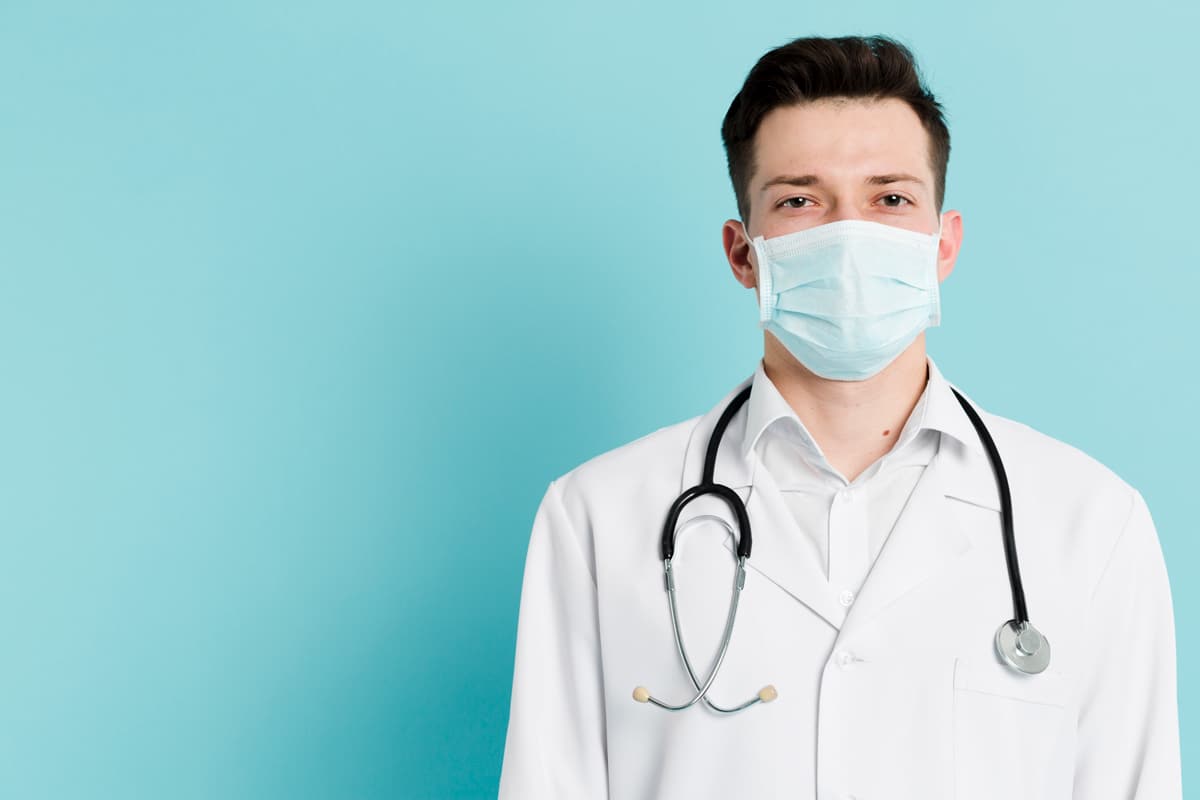 A healthcare provider wearing a mask, stethoscope, and lab coat, on a light blue background.